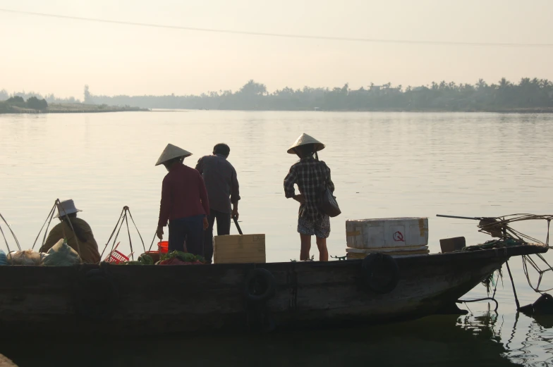 three people standing on the back of a boat with groceries in it