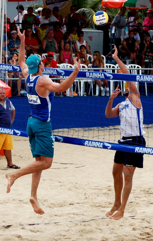 two men are playing volley balls on the sand