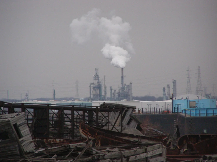 smoke coming out of the factory stacks on top of piles of junk