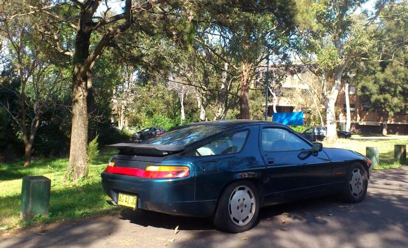 a blue sports car parked on a tree lined road