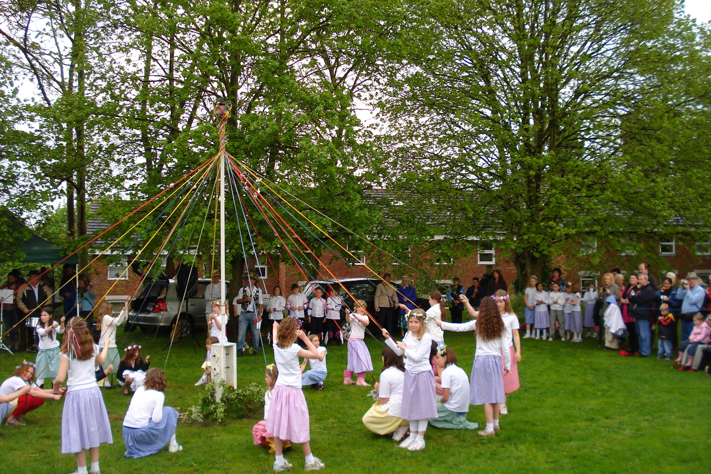 several children dressed in white and pink dresses are dancing near a tent