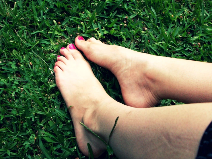 bare feet, with a pink nail and short legs on a grassy field
