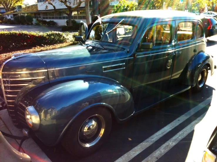 a dark blue vintage car with open hood and no mirror