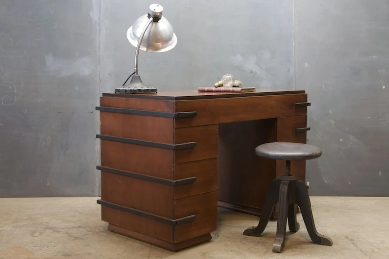 an old fashioned desk with a lamp and chair