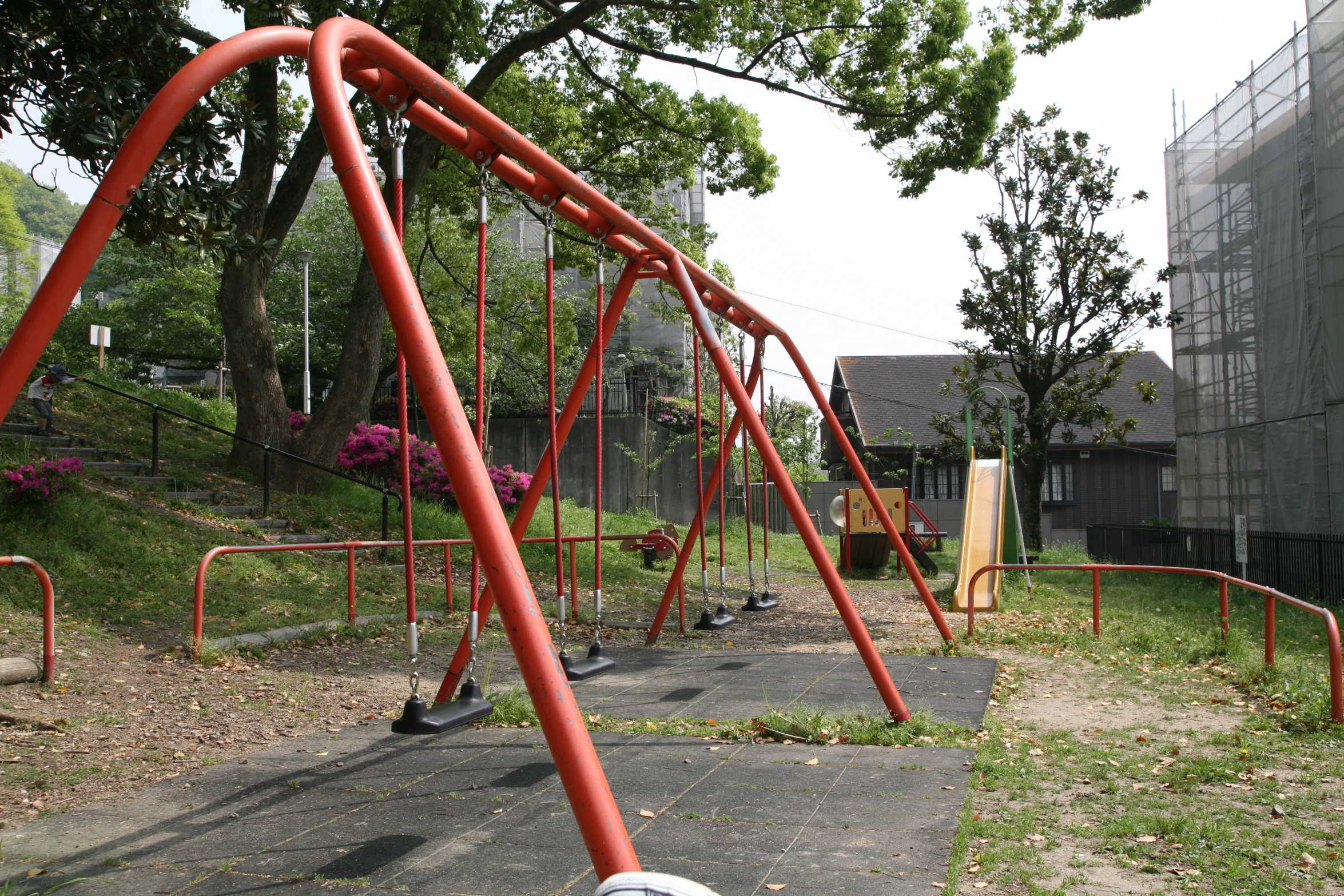 the metal swing is near some trees and building