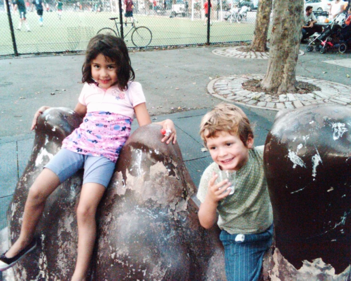 two children posing for a pograph near a playground