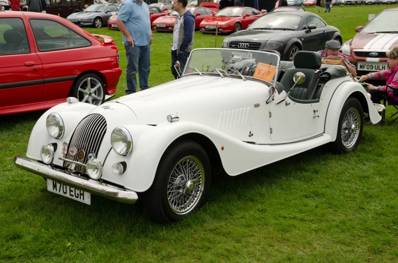 vintage cars and people in the grass at an auto show