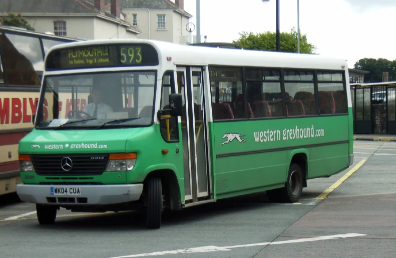 a large long green and white bus on a street