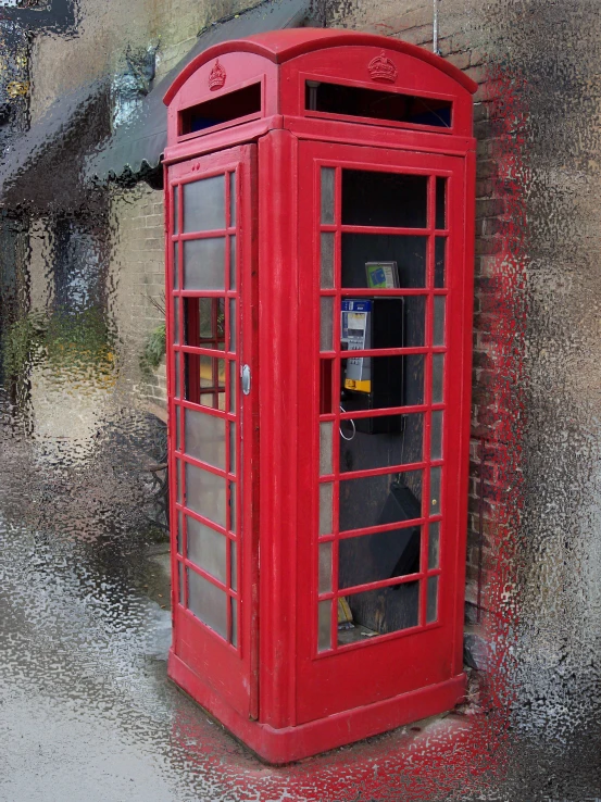 a red telephone booth stands against a wall