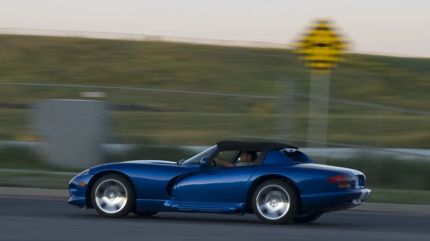 a blue sports car driving around the curve