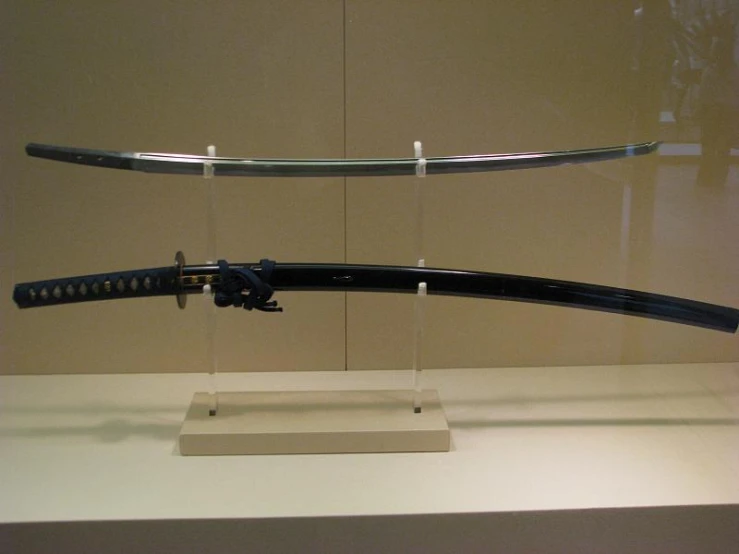 a sword is displayed behind glass with a white stand