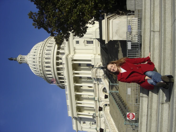 a woman standing outside a large building with a blue sky background