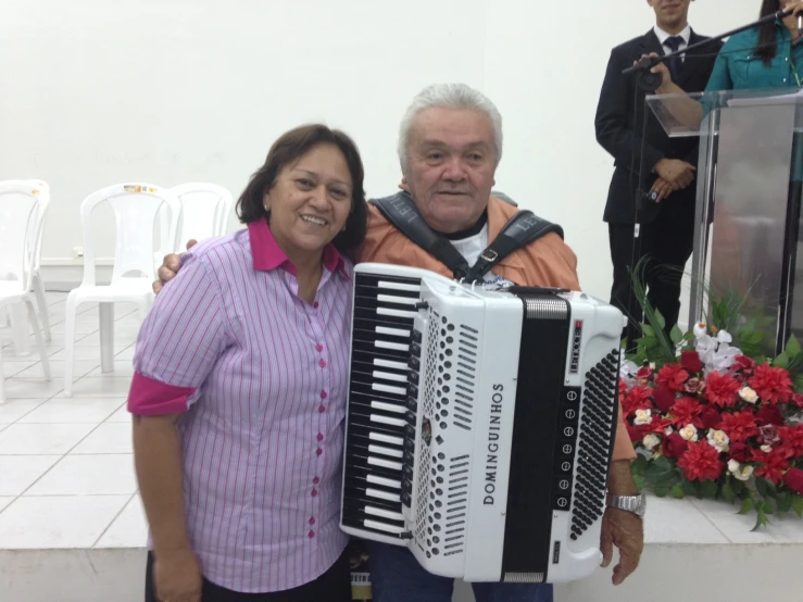 a woman and a man holding an accordion next to a stage