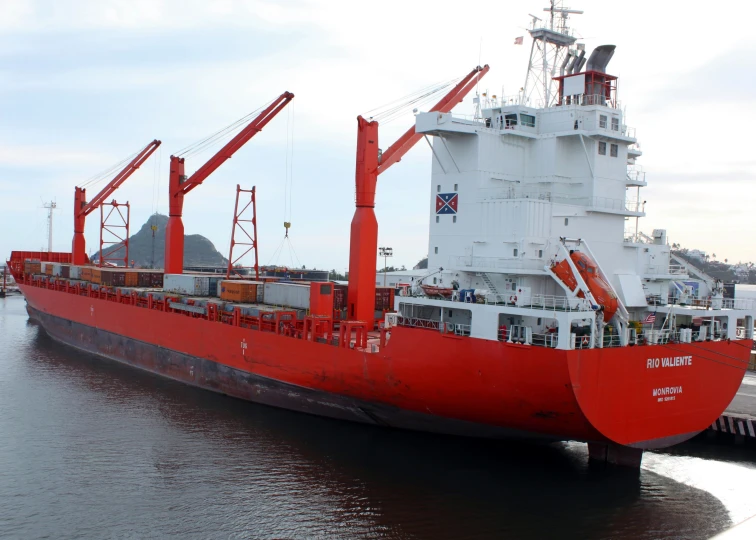 a large red ship docked next to a dock