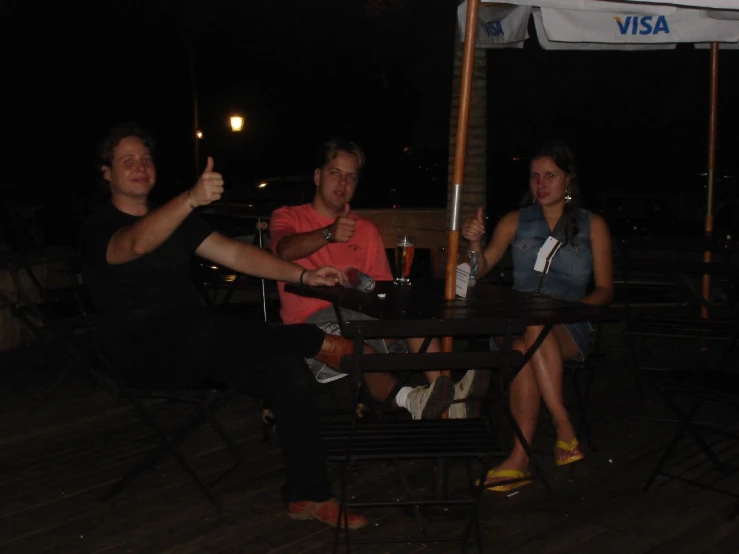 three people sitting around a table in an outdoor area