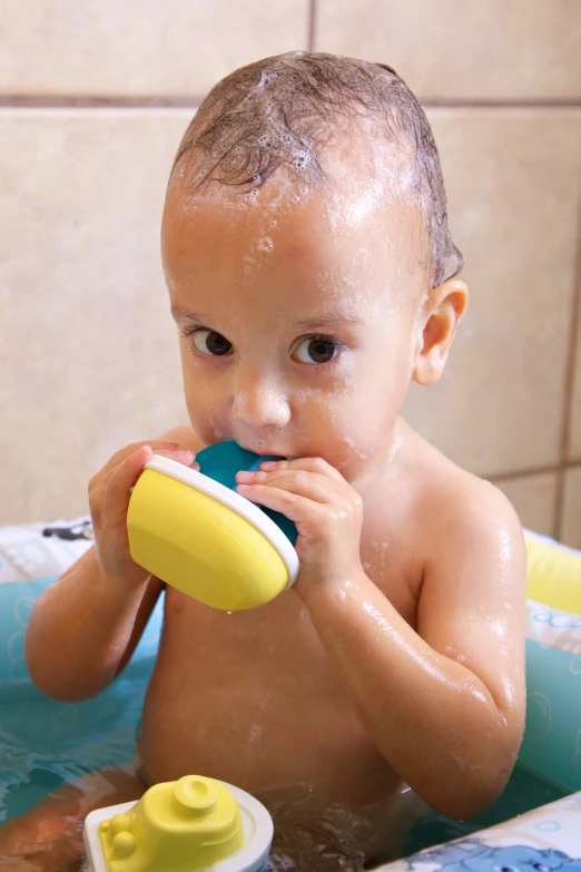 baby sitting in a bath tub playing with a toy