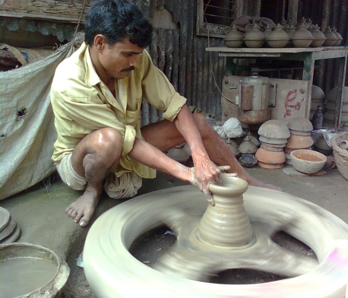 a man working on a pottery wheel outside