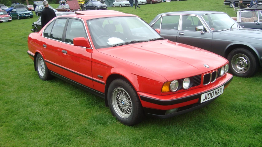 some older cars in a grassy field with others looking at them