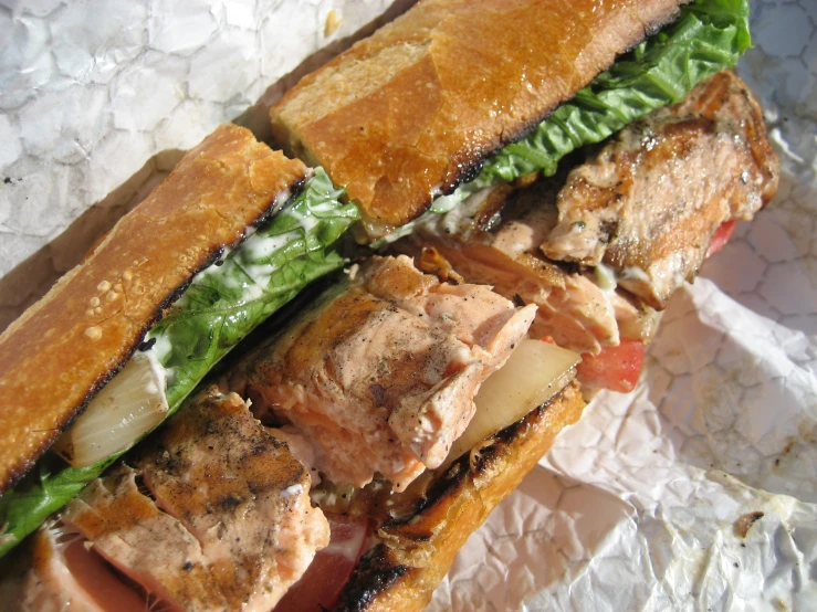 a sandwich is laying on a wrapper, partially eaten