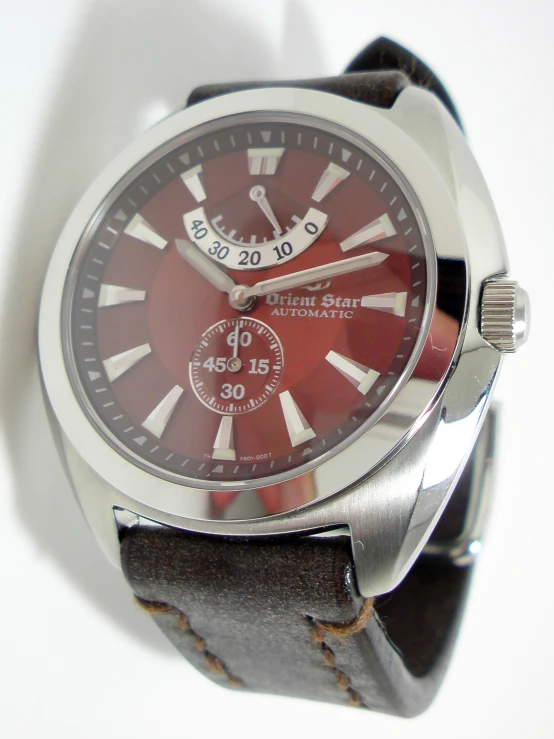 an older style red watch sits upon a plain surface