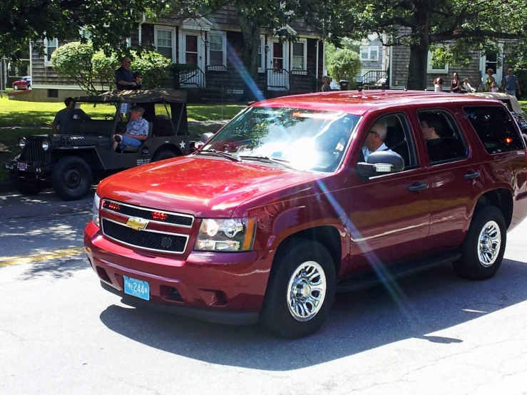 red chevrolet suburban suv with a utility vehicle in the background