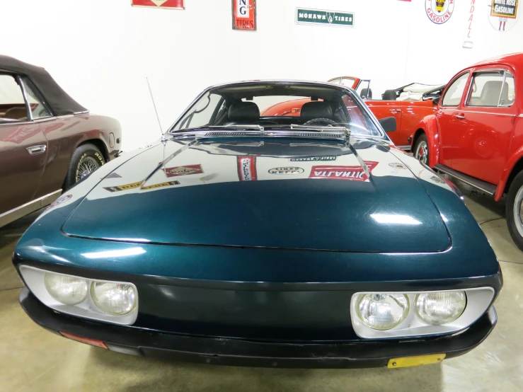 vintage cars sit in a garage with old ones behind them