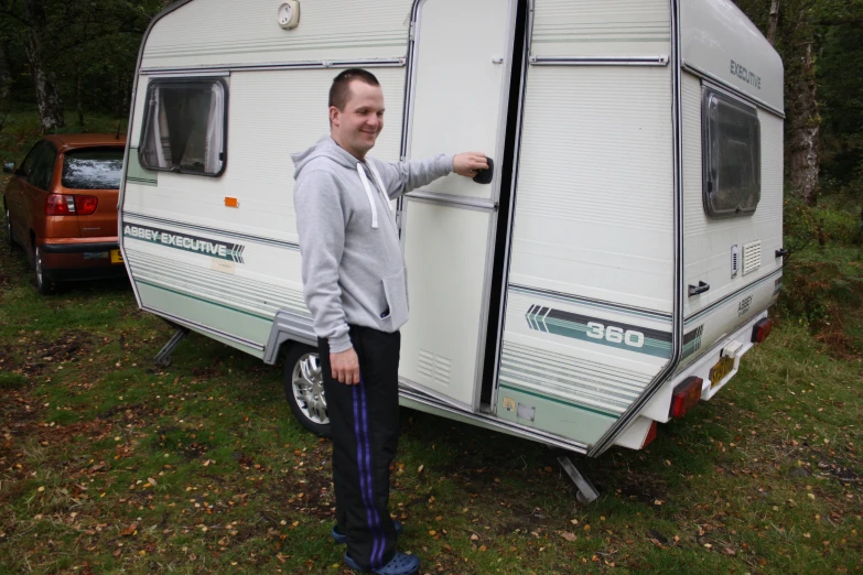 man standing by trailer in grass near truck