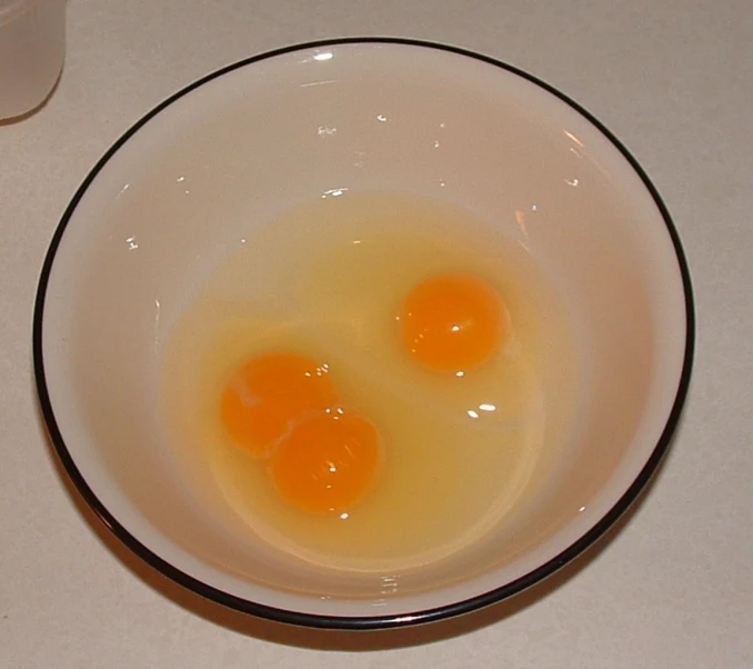two eggs in a bowl sit on a white counter top