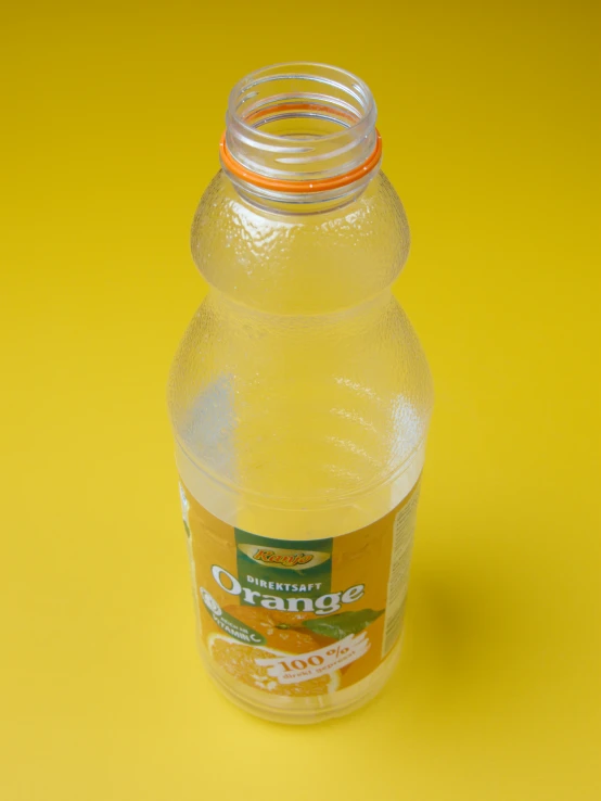 a bottle of orange juice sitting on top of a yellow table