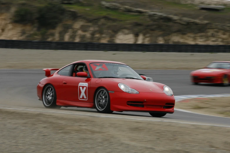 two sports cars driving around a track at speed