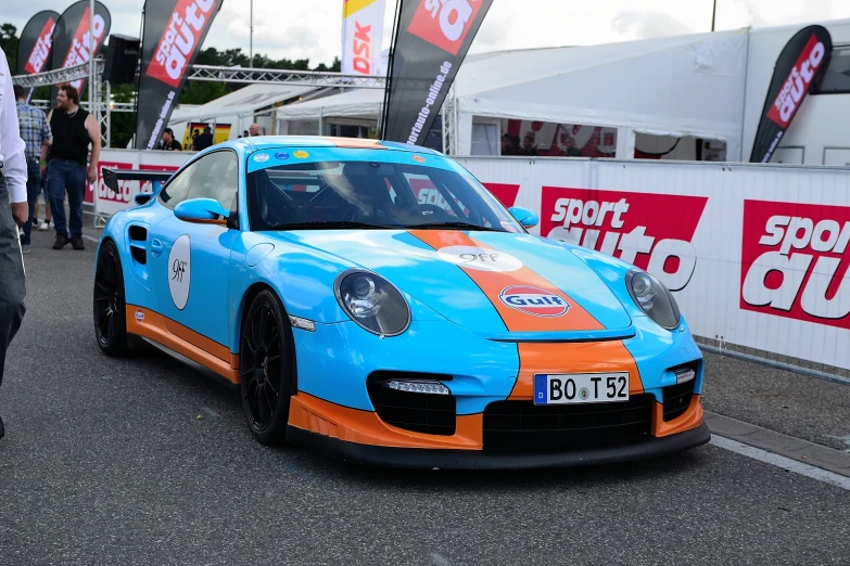 a blue and orange racing car driving down a street