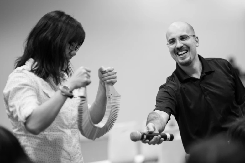 a man and woman in glasses smile holding a device