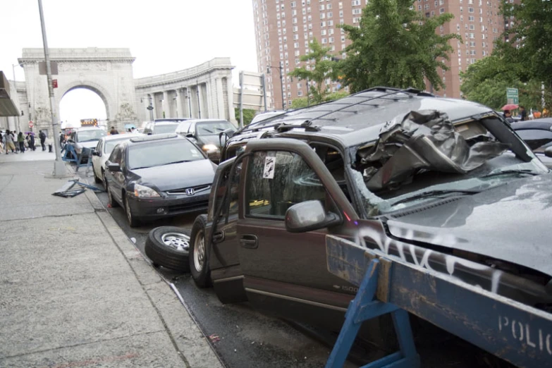 cars are parked on the curb, with one car in the foreground and the other lying on it's side