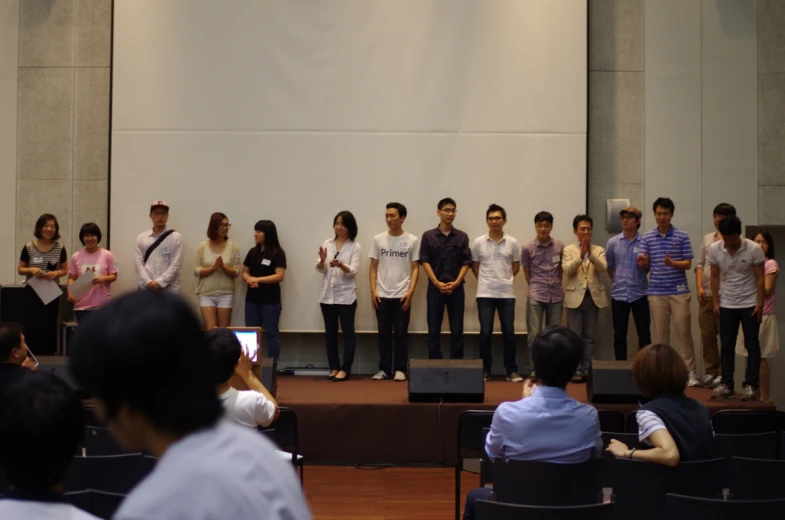 a group of people standing on a stage watching a video