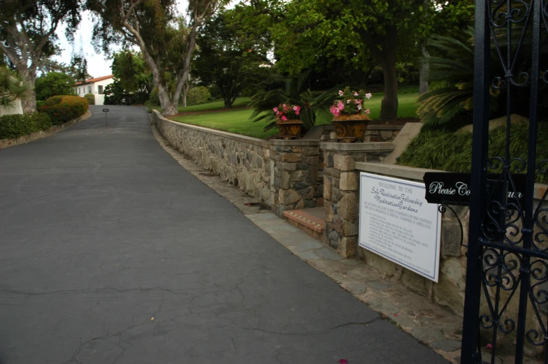 a paved roadway with fence, street and trees