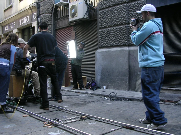 the man is using his cellphone while people stand on the sidewalk