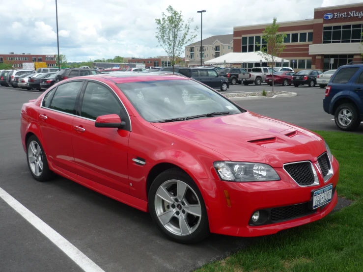 the red pontiac falcon car is parked in a parking lot