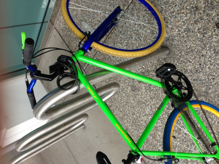 a green bike with yellow bars standing near a fence