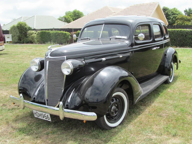 an old black classic car sitting in the grass