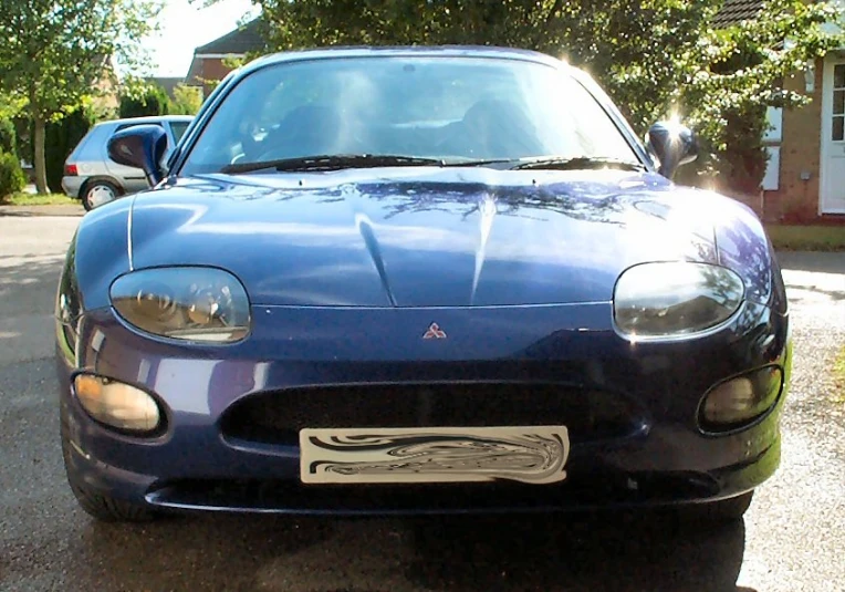 a blue sports car parked in front of a house