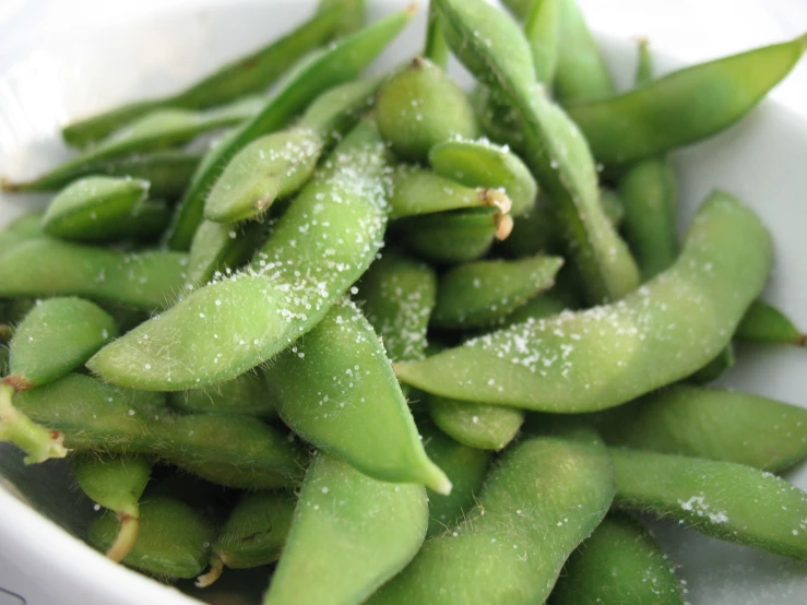 many small green beans are placed in a white bowl