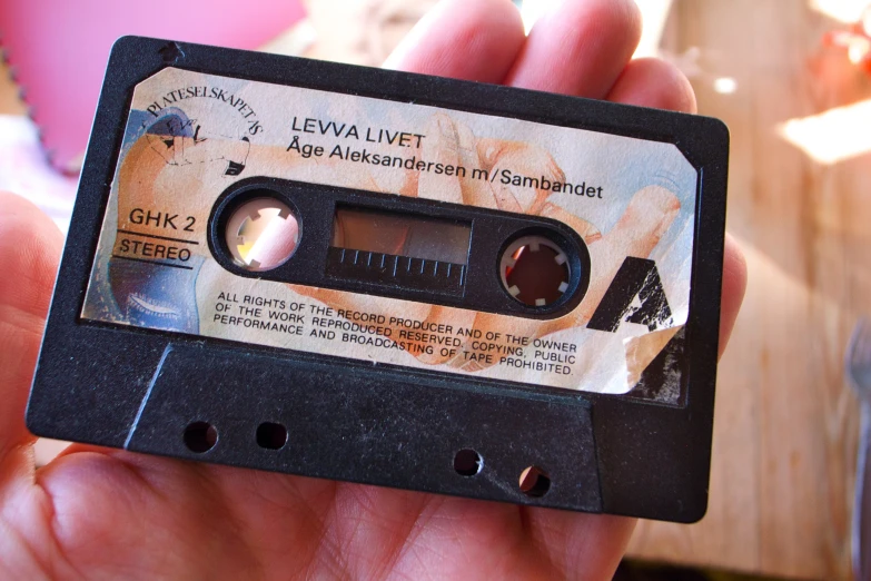 a person is holding a small cassette that has a clock inside