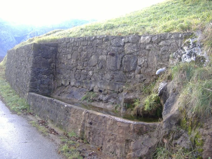 a stone wall with a creek running underneath