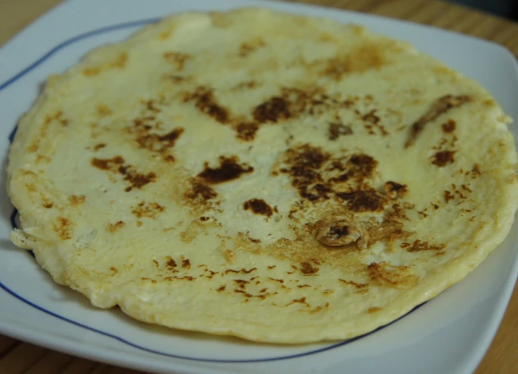 a white plate topped with tortillas sitting on top of a wooden table