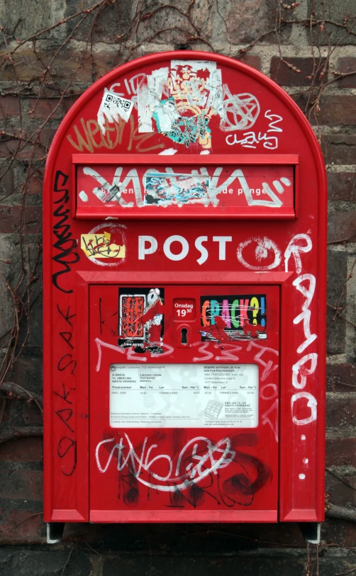 a post box has some graffiti and stickers on it