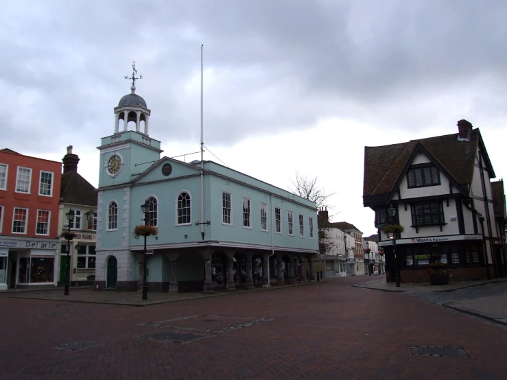 the small town square has an old blue building and many buildings on either side