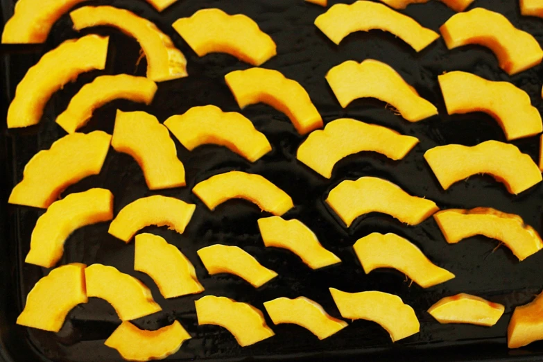 a black and white baking sheet covered in squares of pumpkins