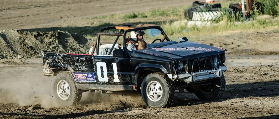 a man in an off - road jeep kicking up dirt