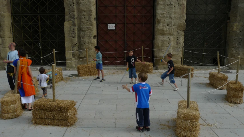 children standing around playing with hay bales and ropes