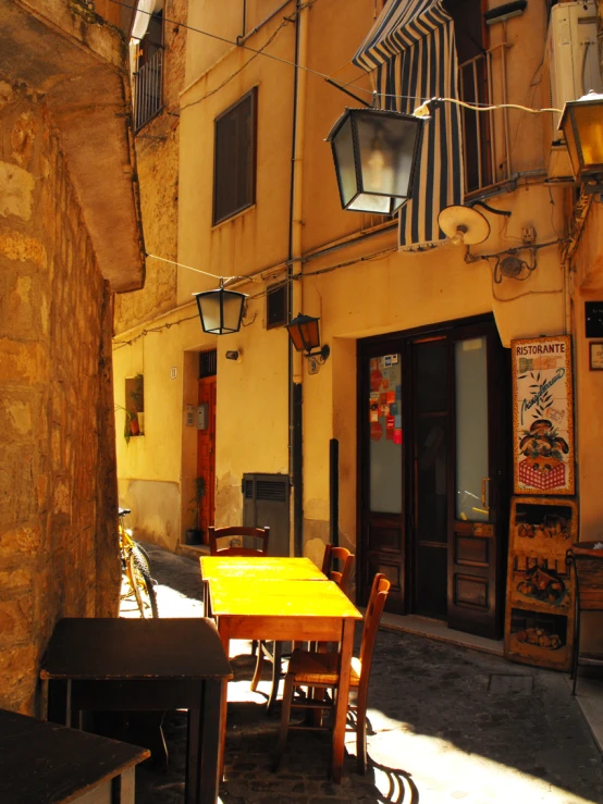 some light hangs over the tables and chairs outside of a building